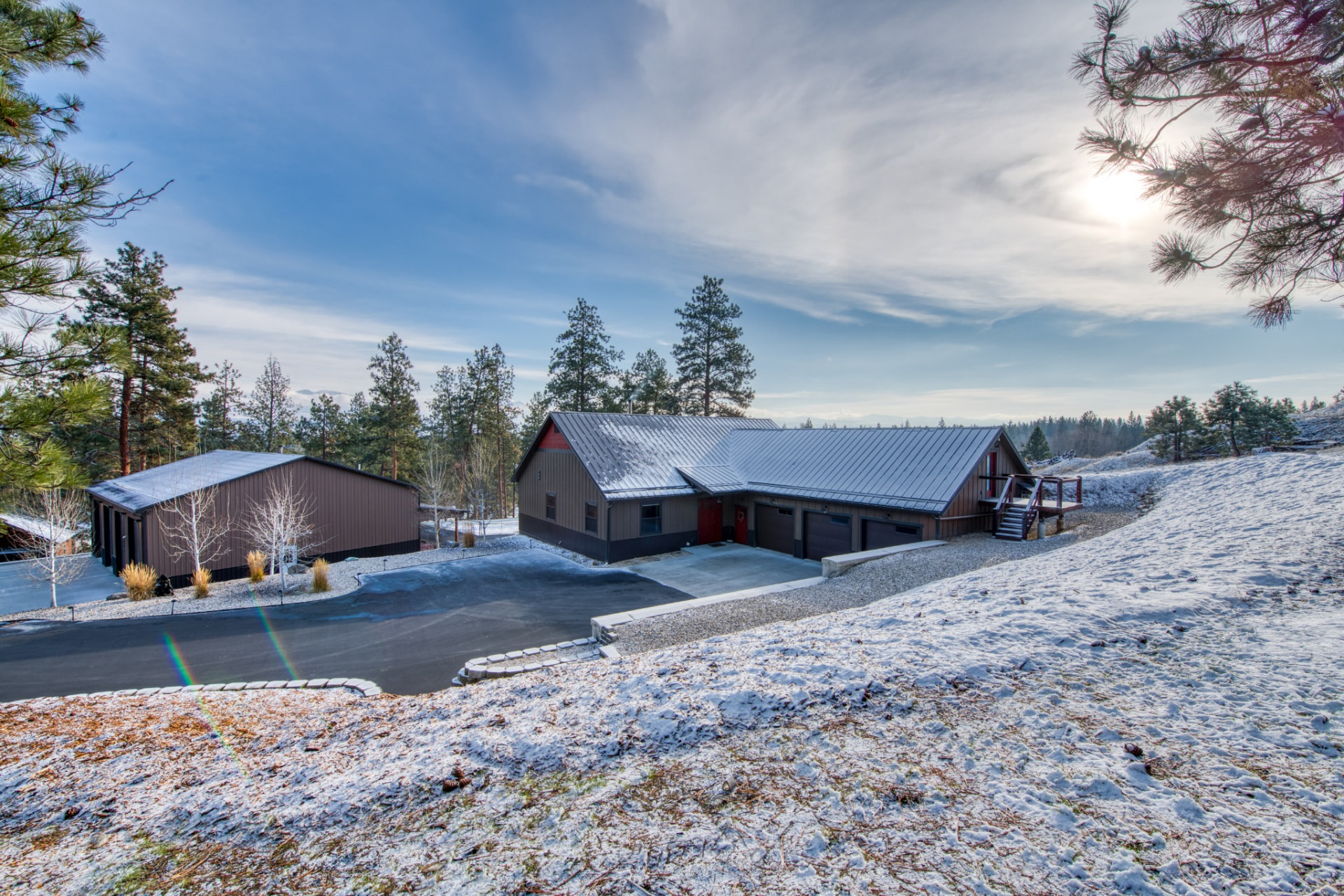 217 Peekaboo Trail main home and shop on a winter morning, surrounded by pines and snowy grounds